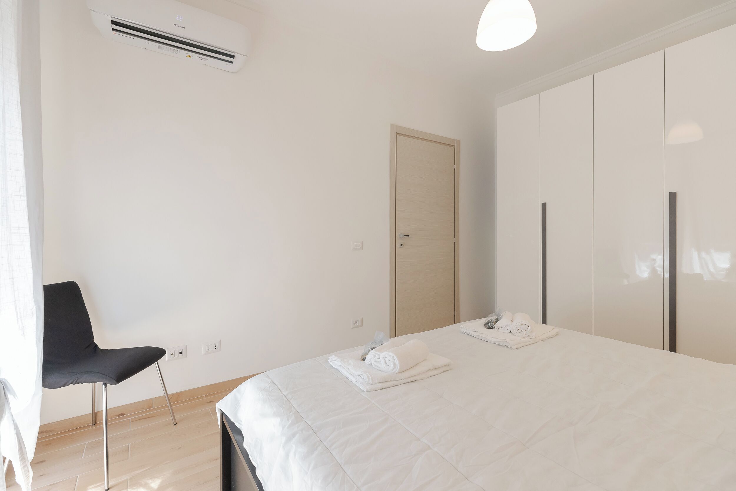 Ein Schlafzimmer mit einem Bett, einem Sessel, einem Kleiderschrank und einer Klimaanlage.