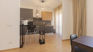 A modern kitchen with a central island, bar stools, and a dining table with chairs. - Moderno e comodo Metro Lucio Sestio (Rome)
