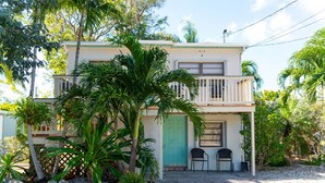 A two-story house with a balcony, a front door, and a small porch area with two chairs. - Cindy Villa - Key Largo (Key Largo)