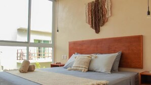 A bedroom with a large bed, a wooden headboard, and a view of the outside. - Gama 09 Apartments -Apartment with balcony (TULUM)