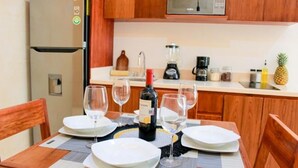 A dining table set with plates, wine glasses, and a bottle of wine. - Gama 09 Apartments -Apartment with balcony (TULUM)