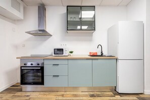 A compact kitchen with a built-in oven, microwave, and a white refrigerator.