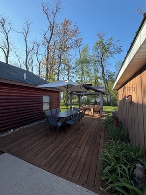 A wooden deck with a table and chairs, a pergola, and a covered seating area. - Otsego Lake Lodge - Your next destination! (Gaylord)