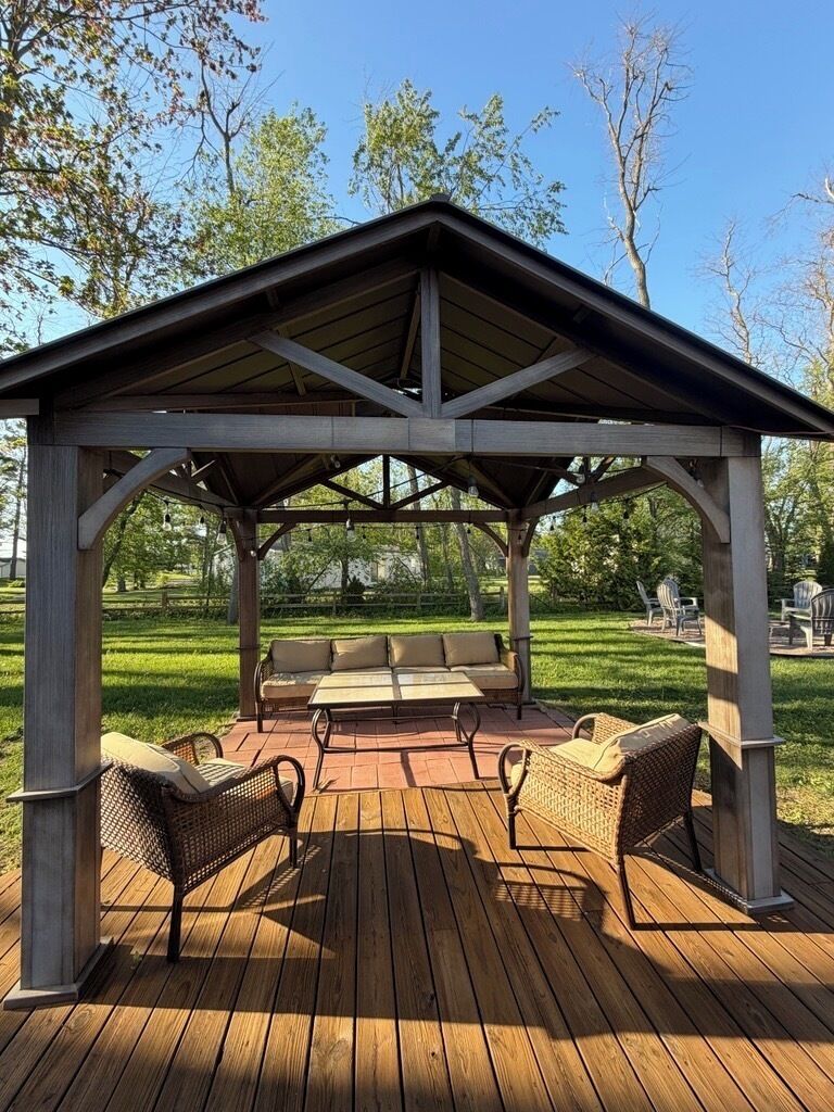 A wooden deck with a covered seating area, including a sofa and chairs.