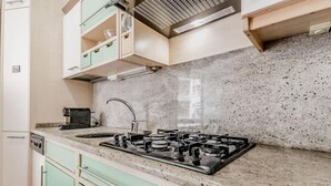 Een keuken met een granieten aanrecht, een gasfornuis en lichtgroene kastjes.