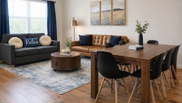 A modern living room with a sofa, coffee table, and dining table with chairs.