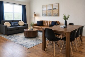 A modern living room with a sofa, coffee table, and dining table with chairs.
