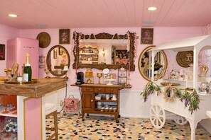 Een kamer in roze tinten, met een kaptafel, spiegels en een klein karretje met decoratieve objecten.