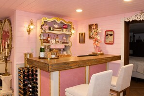 Een bar met een houten toonbank, een wijnrek en een bord met de tekst 'SHE SHED BLVD'.