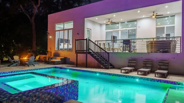 Una casa moderna con piscina, un patio cubierto y una escalera que lleva a un balcón.