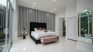 Een moderne slaapkamer met een groot bed, een zwart hoofdeinde en een gestreept wandpaneel.