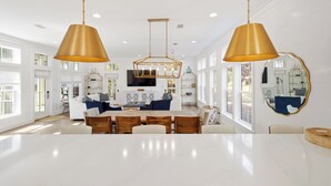 Een ruime keuken met een groot kookeiland, hangende lampen en een moderne eethoek.