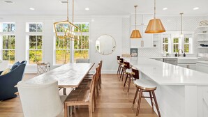 Een moderne keuken met een groot eiland, houten barkrukken en hanglampen.
