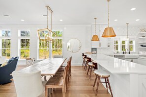 A modern kitchen with a large island, wooden bar stools, and pendant lighting. - 30A Caspian Blue Cottage, Luxury Retreat Magnolia Cottages | 6Str Golf Cart (Inlet Beach)
