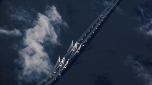 Vista aérea de un puente con múltiples carriles y cielo despejado con nubes.