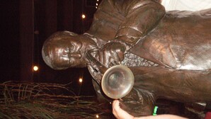 Una estatua de bronce de un hombre sosteniendo una trompeta.