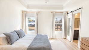 Un'ampia camera da letto con un letto grande, una porta scorrevole per il bagno e vista all'esterno.