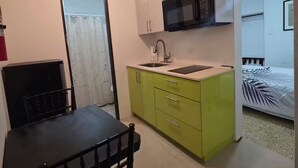 A compact kitchen with a dining table and chairs, a microwave, and a sink. - Unit 2@Casa Catalina-City, Culture, & Coastline (San Juan)