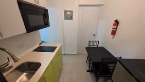 A compact kitchen with a microwave, sink, and dining table. - Unit 2@Casa Catalina-City, Culture, & Coastline (San Juan)
