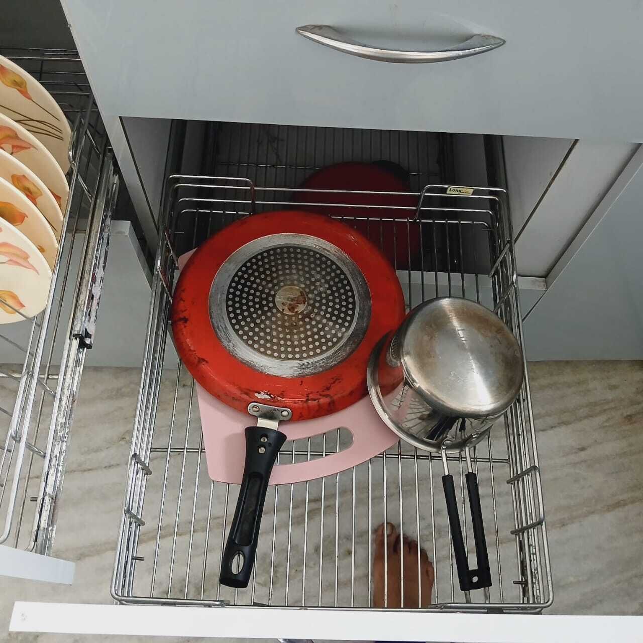 Une cuisine avec un égouttoir contenant une poêle rouge et une casserole.