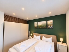 Ein Hotelzimmer mit einem Bett, zwei Nachttischen, einem Kleiderschrank und drei Landschaftsbildern an der Wand.