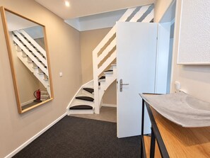 Ein modernes Interieur mit einer weißen Treppe, einer Tür und einem kleinen Tisch mit abgerundeter Kante.