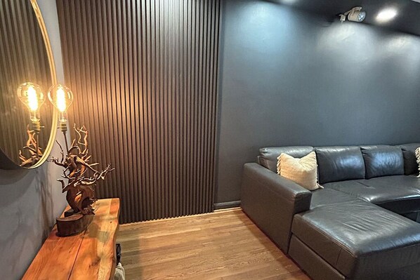 Ein modernes Wohnzimmer mit einem dunkelgrauen Sofa, einer Holzbank und einer dekorativen Leuchte.