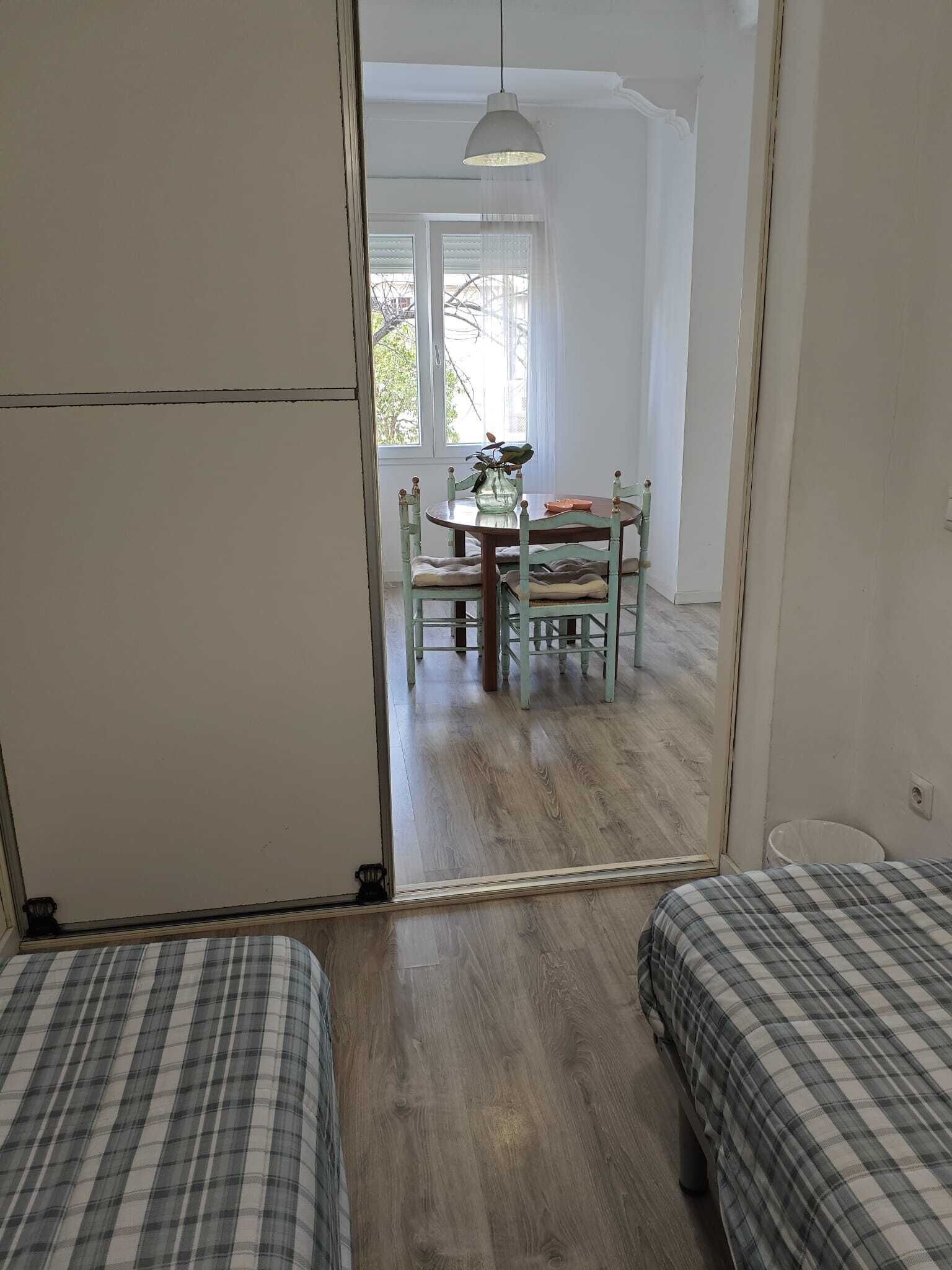 Una habitación con dos camas, una mesa de comedor con sillas y una lámpara colgante.