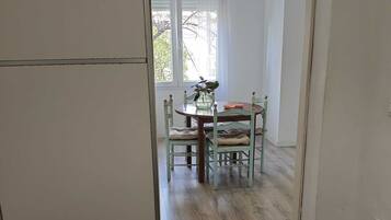 Una habitación con dos camas, una mesa de comedor con sillas y una lámpara colgante.
