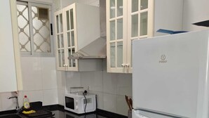 A modern kitchen with white cabinets, a black countertop, a built-in oven, a microwave, and a refrigerator. - Nice apartment in quiet neighborhood near downtown (València)