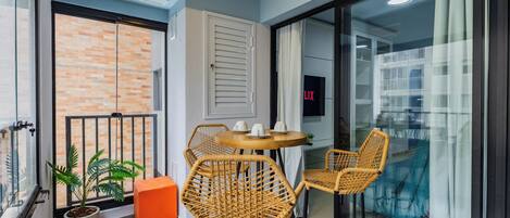 A balcony with wicker chairs, a small table, and a potted plant.