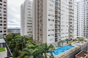 Un immeuble résidentiel de grande hauteur doté de nombreux balcons, d’un jardin sur le toit et d’une piscine.