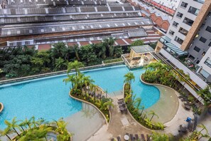 Une grande piscine intérieure divisée en plusieurs zones, entourée d’une végétation luxuriante et agrémentée d’espaces de détente en plein air.
