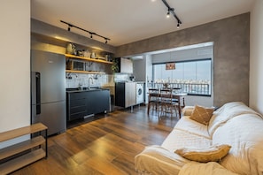 Een modern appartement met keuken, eethoek en groot raam met uitzicht op de stad.