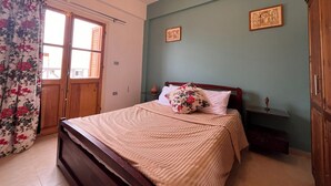 Ein Schlafzimmer mit einem Bett, einem Holzschrank, einem kleinen Nachttisch und einem Fenster mit Vorhängen.