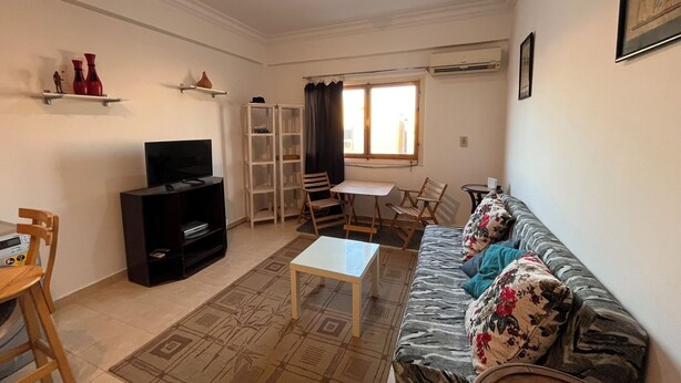 Ein Wohnzimmer mit einer Couch, Fernseher und einem Essbereich mit Stühlen und Tisch.