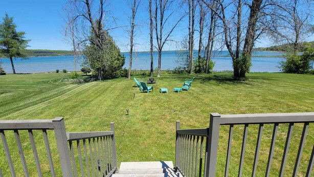 A grassy deck with a view of a lake and trees.