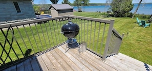 A deck with a barbecue grill, a small shed, and a view of a lake. - Entire House by beautiful Georgian Bay (Wiarton)