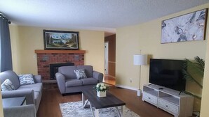 A living room with a fireplace, sofas, a coffee table, a TV, and a painting on the wall.