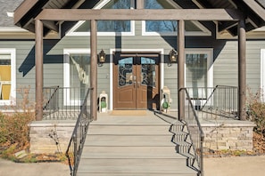 A house with a front porch, a double door with decorative glass, and a stone pathway leading to the entrance.