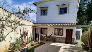 Una casa de dos pisos amb un patí, un hamaca i un jardí petit.