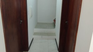 Un passadís amb dues portes de fusta, un sòl de rajola i una escala que mena a un nivell superior.