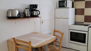 Una piccola cucina con tavolo e sedie, un forno a microonde, un frigorifero e un piano cottura.