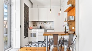 Una cocina moderna con armarios blancos, una mesa de comedor de madera y sillas de metal.