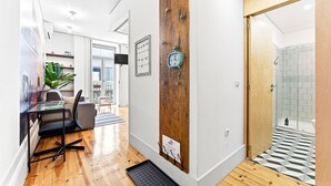 Un interior moderno con una pared de acento de madera, una zona de comedor con mesa y sillas, y un cuarto de baño con paredes de azulejos.