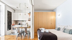 Un dormitorio moderno con cama, mesitas de noche y vistas a una zona de cocina.