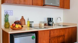 A compact kitchen with wooden cabinets, a stainless steel refrigerator, a microwave, a sink, and a coffee maker. - Gama 09 Apartments - Studio with balcony (TULUM)