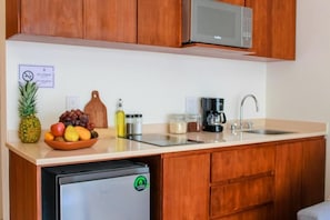 A compact kitchen with wooden cabinets, a stainless steel refrigerator, a microwave, a sink, and a coffee maker. - Gama 09 Apartments - Studio with balcony (TULUM)