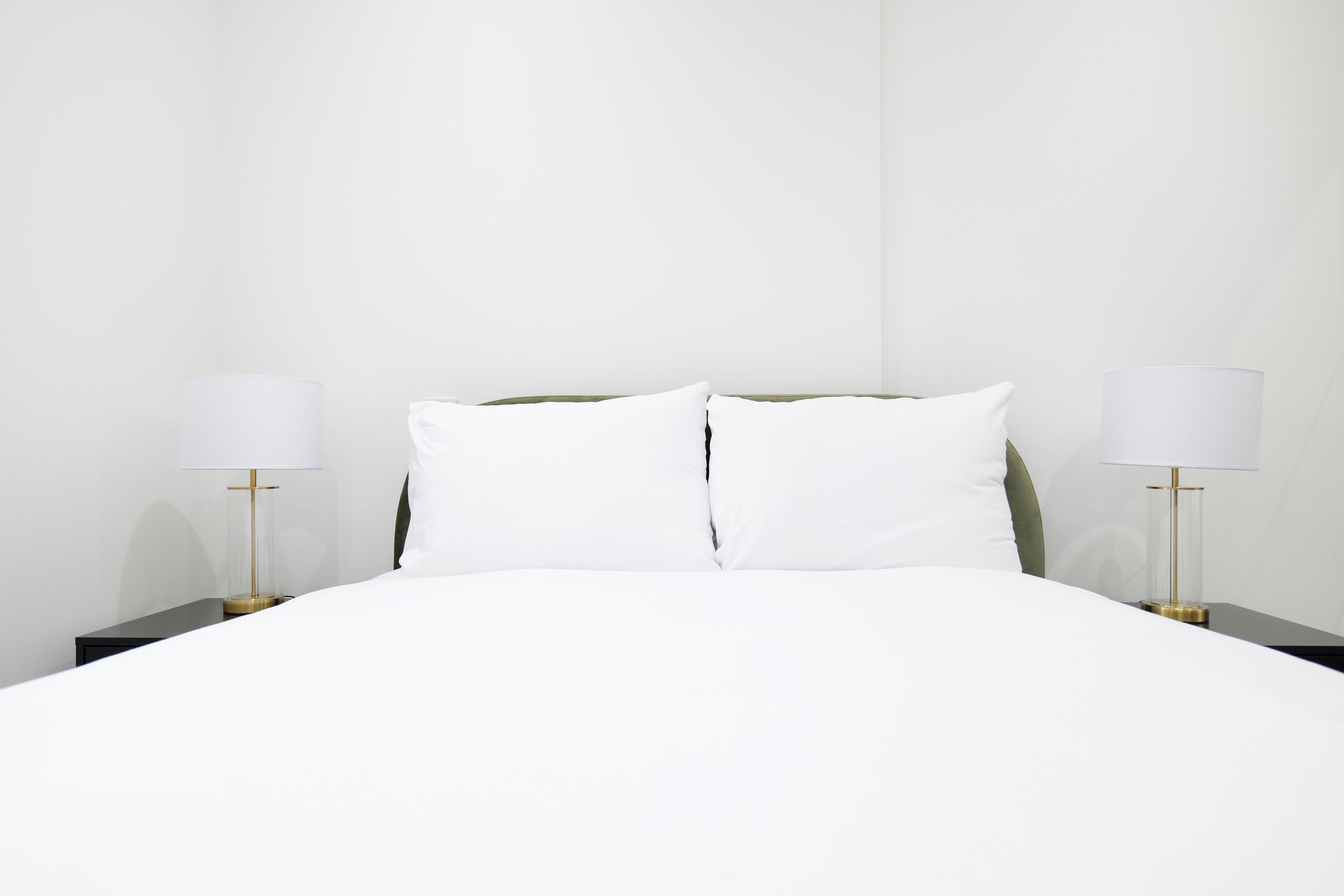 A hotel room with a large bed, two bedside tables, and two lamps.