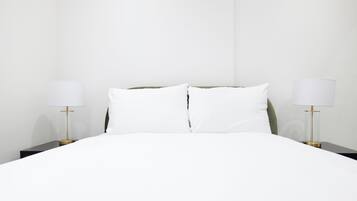 A hotel room with a large bed, two bedside tables, and two lamps.
